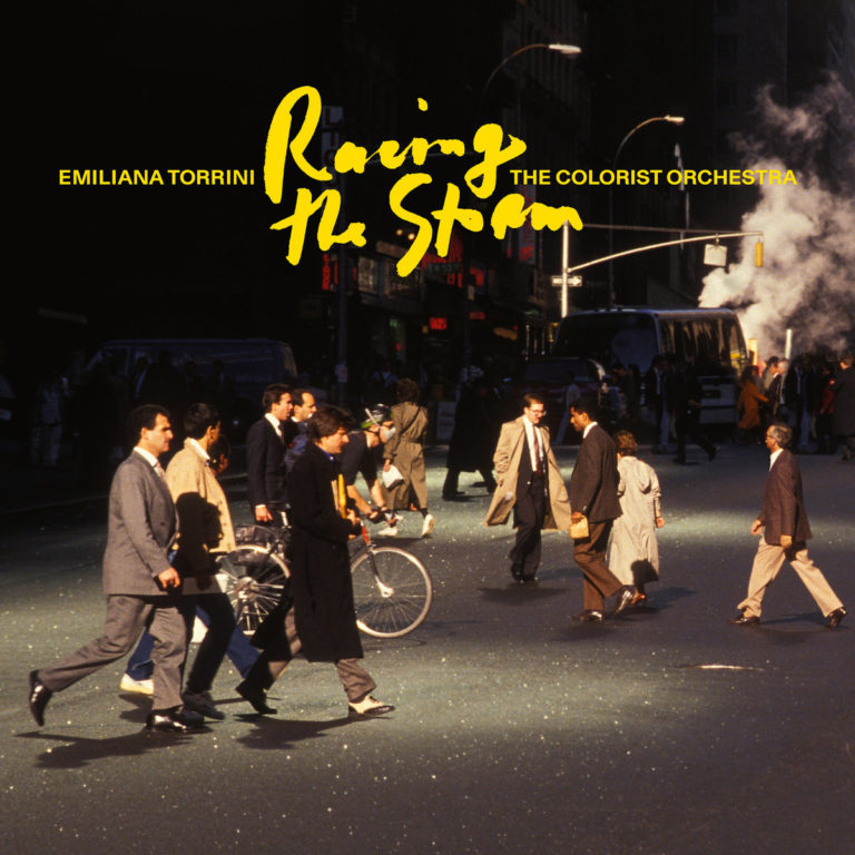 Menschen in Business-Outfits überqueren eine Straßenecke in einer Großstadt, dampfende Kanalisation im Hintergrund – Cover des Albums "Racing the Storm" von Emilíana Torrini & The Colorist Orchestra.