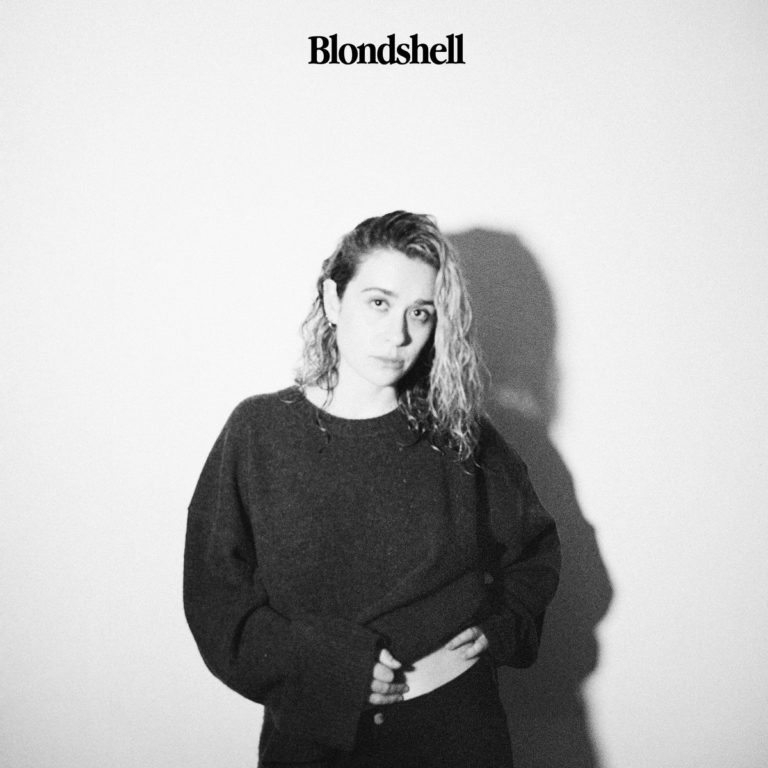 Albumcover von Blondshell: Schwarz-weiß Porträt der Künstlerin Sabrina Teitelbaum vor leerer Wand, leicht melancholischer Blick, Schattenwurf im Hintergrund.