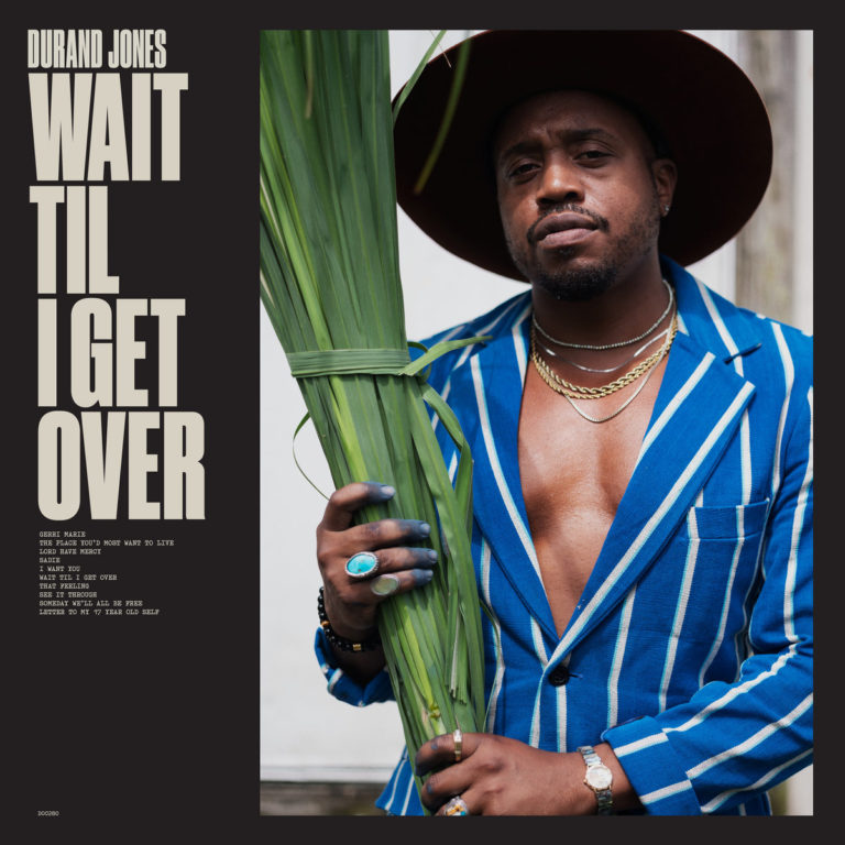 Albumcover von „Wait Til I Get Over“ zeigt Durand Jones in blau-weiß gestreiftem Anzug und Hut, mit Palmblättern in der Hand vor neutralem Hintergrund.