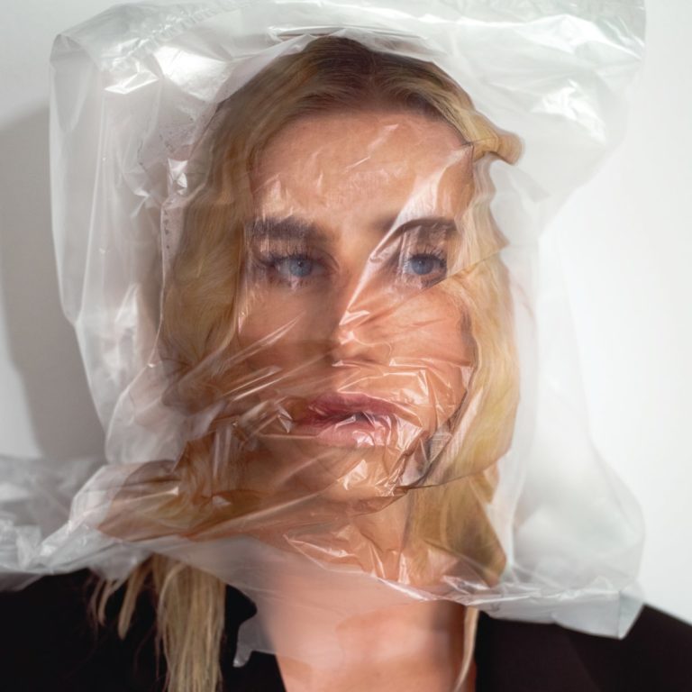 Cover von „Gag Order“ zeigt Kesha mit leerem Blick, ihr Gesicht unter einer durchsichtigen Plastiktüte – Symbol für Erstickung und Kontrolle.