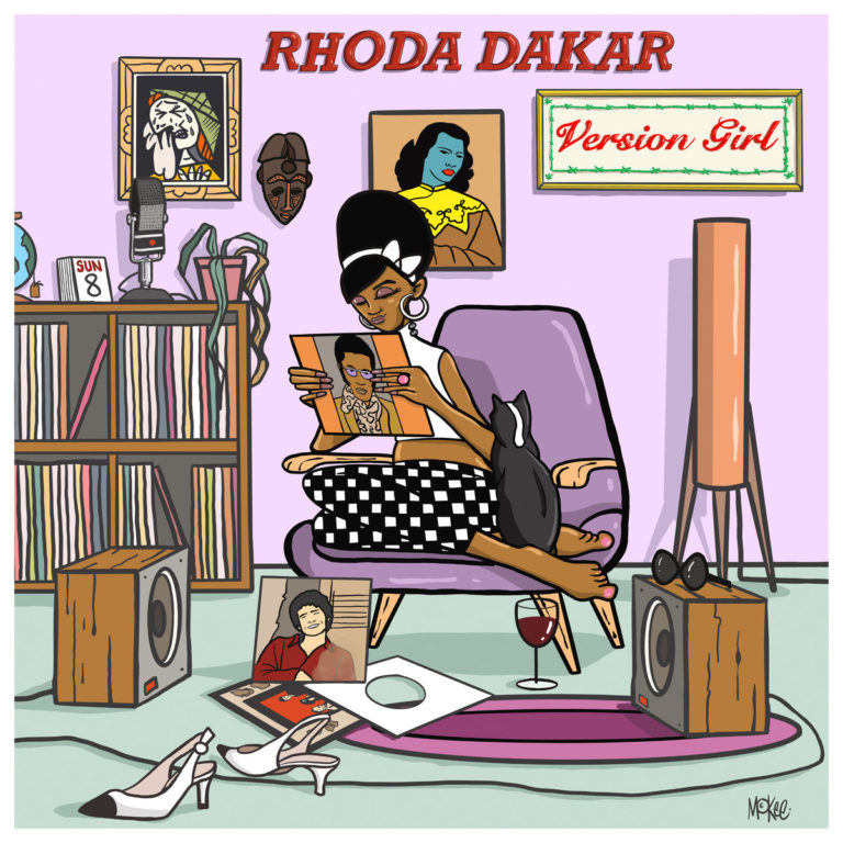 Comic-Cover von „Version Girl“ zeigt Rhoda Dakar auf einem Sessel mit Schallplatten, Katze, Weinglas und Retro-Wohnzimmer voller Pop-Art und Reggae-Flair.