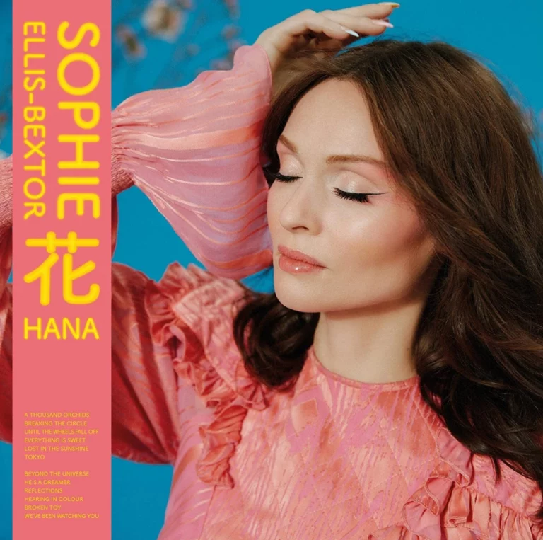 Sophie Ellis-Bextor mit geschlossenen Augen in rosa Kleid vor türkisfarbenem Hintergrund – Cover des Albums HANA, inspiriert von einer Japan-Reise.