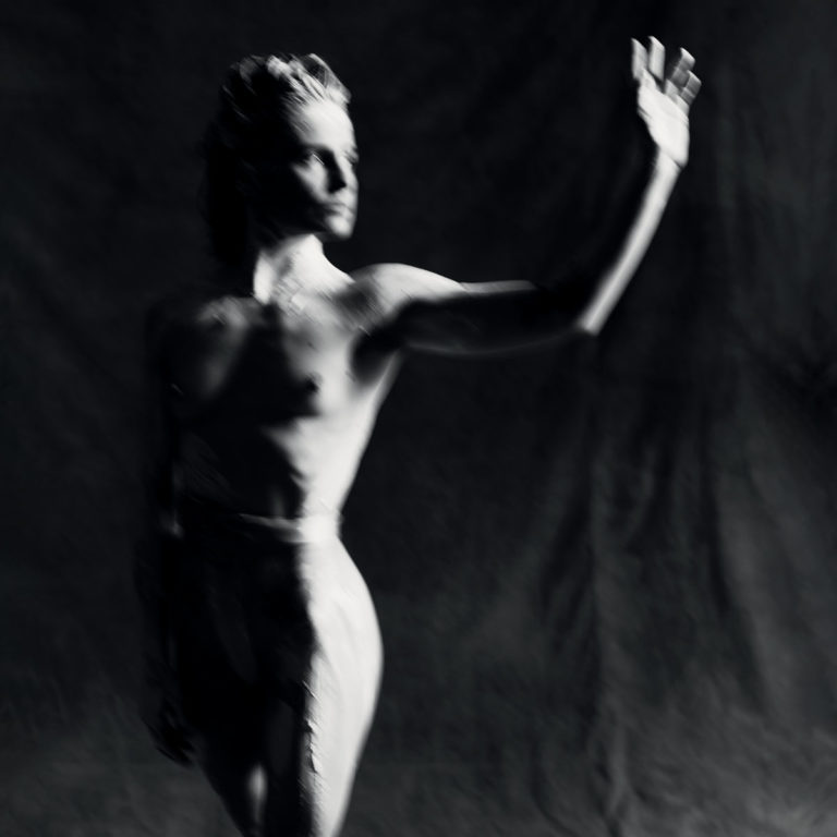 Cover von „PARANOÏA, ANGELS, TRUE LOVE“ – schwarz-weißes, unscharfes Porträt von Christine and the Queens, erhobene Hand, nackter Oberkörper, dramatisch inszeniert.