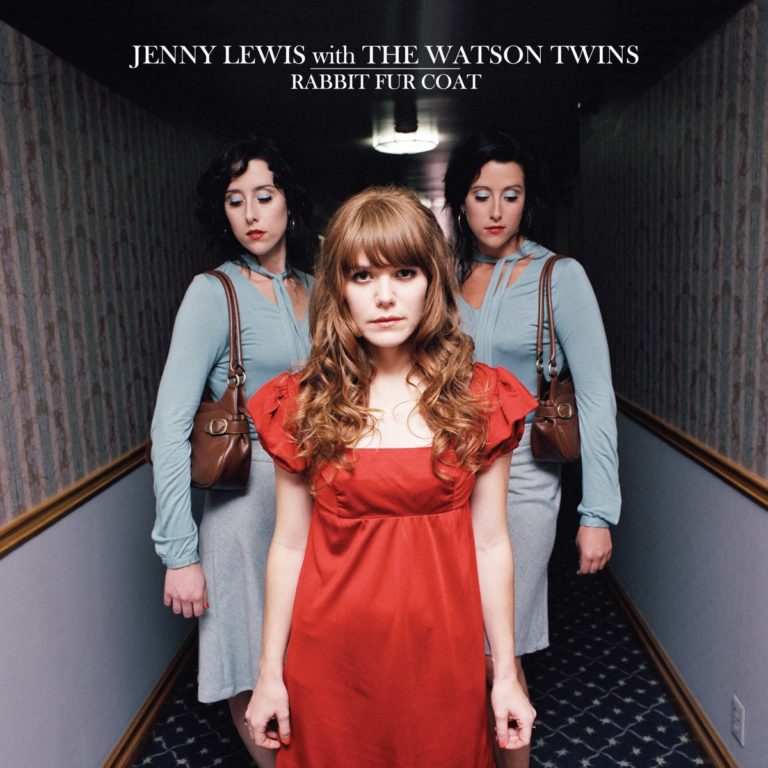 Jenny Lewis in rotem Kleid mit den Watson Twins in einem Flur.