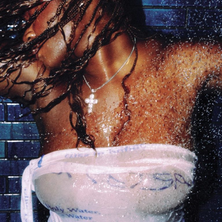 Cover des Albums „Fountain Baby“ von Amaarae – Nahaufnahme einer tanzenden, nassen Brustpartie mit glitzernden Wassertropfen, Kreuzkette und transparentem Stoff vor blauen Fliesen.