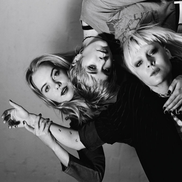 Albumcover von „Dream Wife“: Die drei Bandmitglieder posieren vor einem dunkelgrauen Hintergrund, mit direktem Blick in die Kamera.​