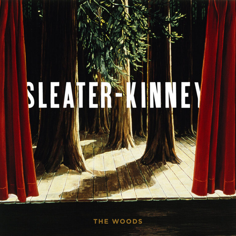 Bühne mit Waldkulisse und roten Vorhängen, Schriftzug Sleater-Kinney.