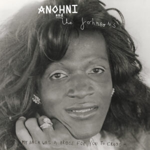 Schwarz-weiß Porträt einer Frau mit glamourösem Styling und warmem Lächeln, Cover des Albums „My Back Was A Bridge For You To Cross“ von ANOHNI and the Johnsons.