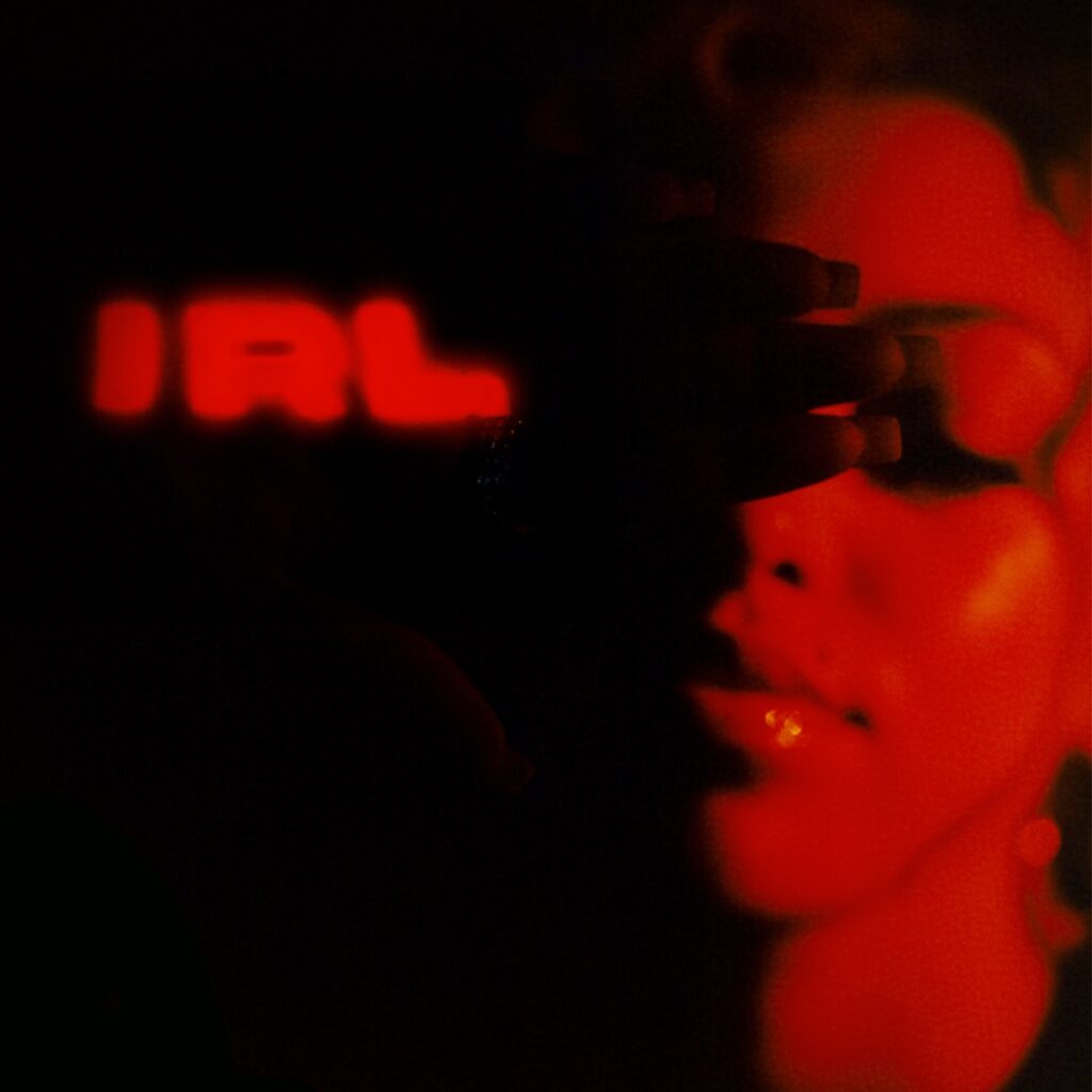 Cover von Mahalias Album „IRL“ mit verschwommen rotem Schriftzug und ihrem halb verdeckten, rot beleuchteten Gesicht in dunkler, intimer Atmosphäre.