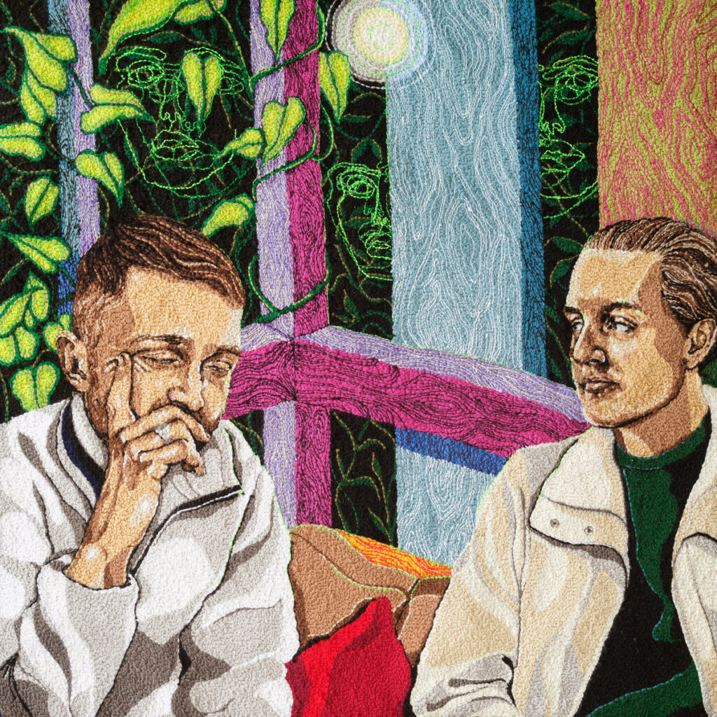 Gesticktes Albumcover von Disclosure: Zwei Männer sitzen auf einem Sofa vor buntem Fensterrahmen, Pflanzen im Hintergrund – Motiv zu Alchemy.