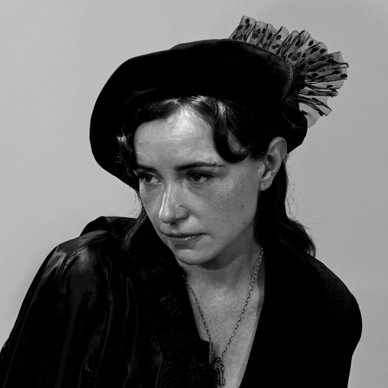 Schwarz-weißes Porträt von Laura Groves mit melancholischem Blick, Samthut und Spitzenverzierung – minimalistisches Cover zu „Radio Red“.