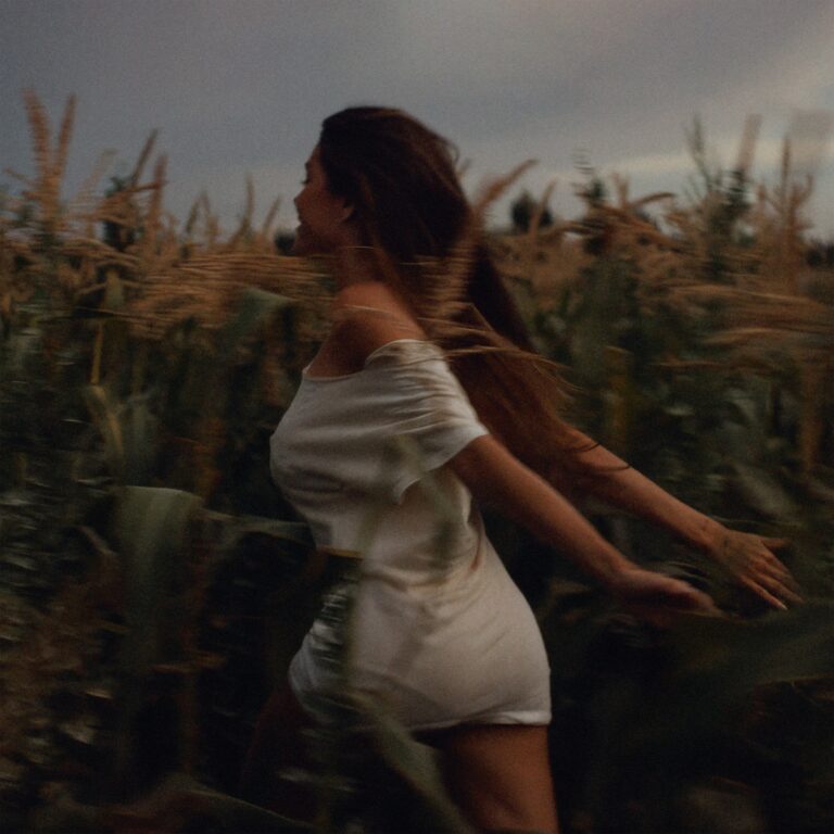 Frau in weißem Kleid läuft verträumt durch ein Maisfeld im Abendlicht – Symbolbild zur emotionalen Reise auf Madison Beers Album Silence Between Songs.