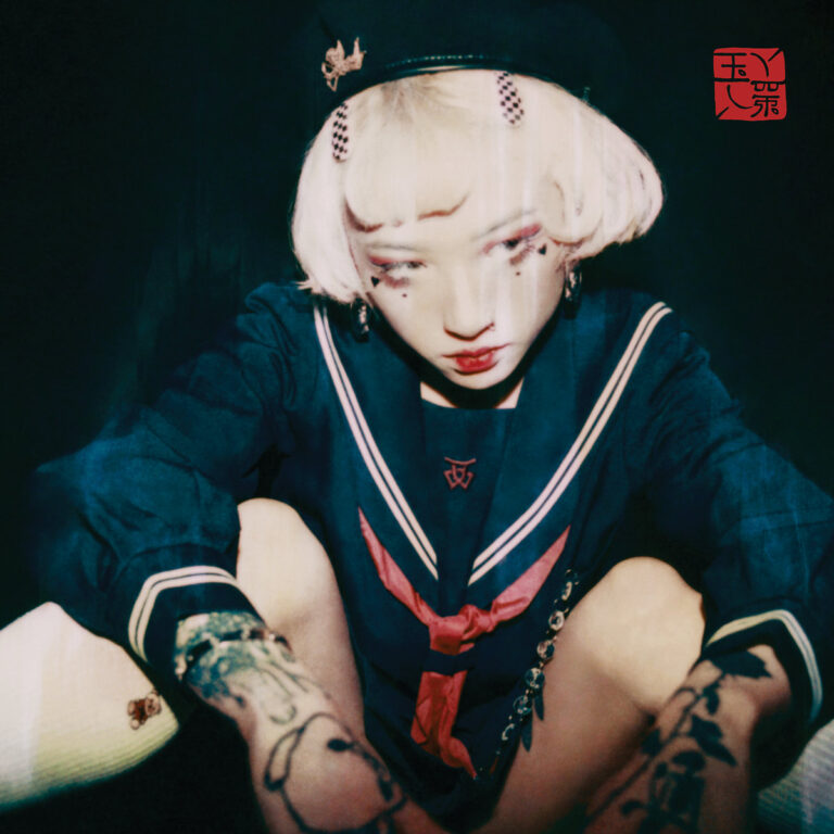 Yeule im dunklen Setting mit Matrosenkleidung und Tattoos, verträumter und melancholischer Blick – Cover des Albums „Serotonin II“.