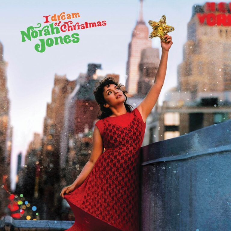 Albumcover von Norah Jones – „I Dream of Christmas“: Die Sängerin im roten Kleid hält einen glitzernden Weihnachtsstern vor nächtlicher Skyline von New York.