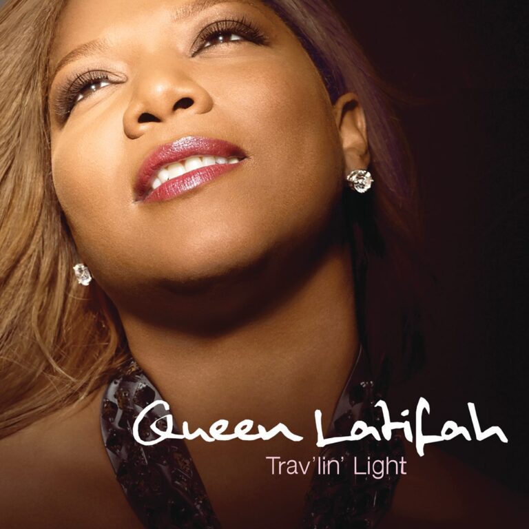 Nahaufnahme von Queen Latifah mit glänzendem Lippenstift und Ohrringen vor dunklem Hintergrund.