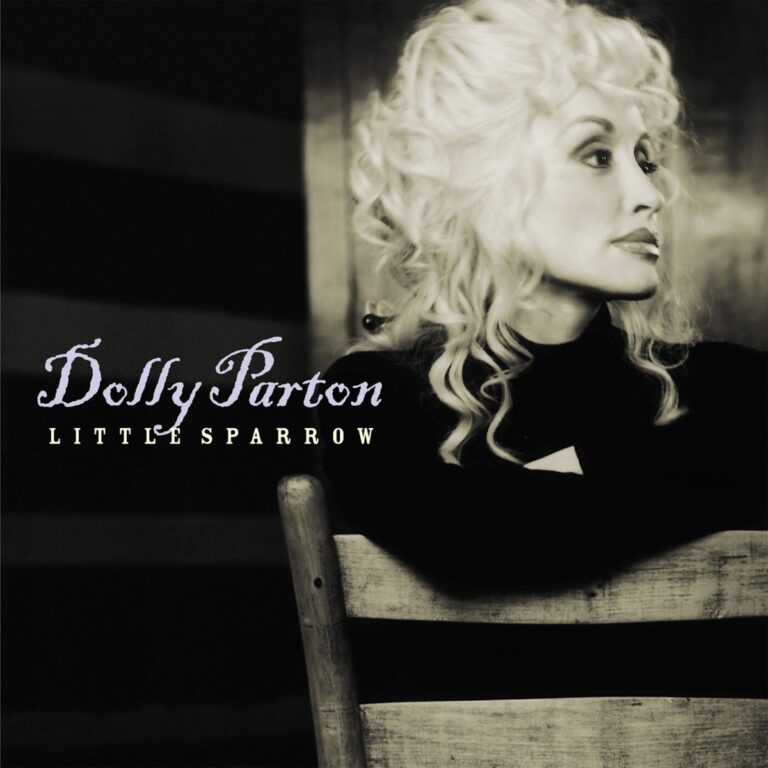 Schwarz-weiß Porträt von Dolly Parton, die auf einem Stuhl sitzt.