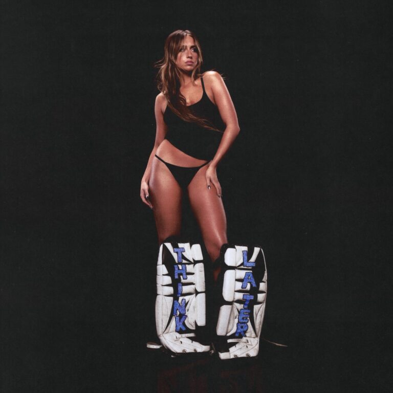 Tate McRae posiert im schwarzen Outfit mit weißen Hockey-Schonern, auf denen „Think Later“ steht – Cover ihres Albums „THINK LATER“.