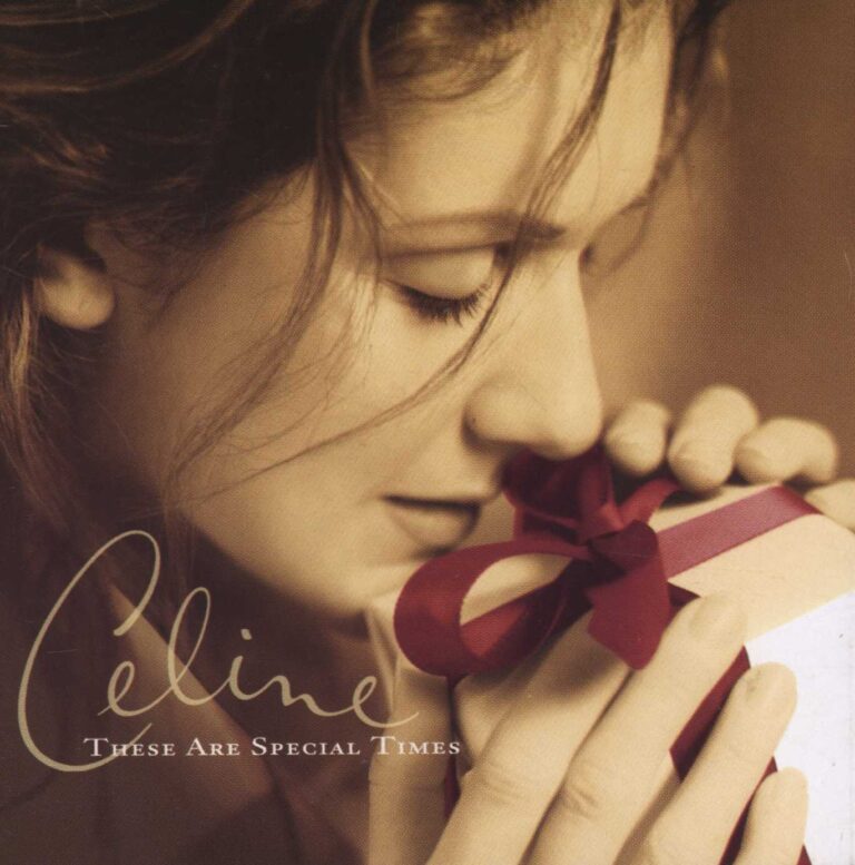 Céline Dion hält ein Geschenk mit roter Schleife nah an ihr Gesicht.