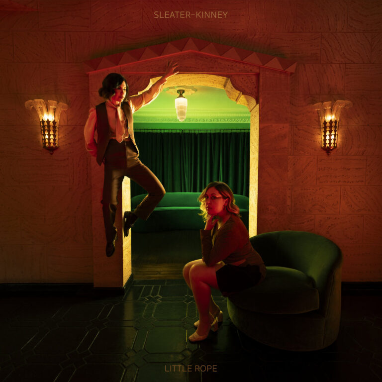 Sleater-Kinney auf dem Cover von „Little Rope“ in einem surreal ausgeleuchteten Raum – visuelles Sinnbild für emotionale Tiefe und intime Dringlichkeit.