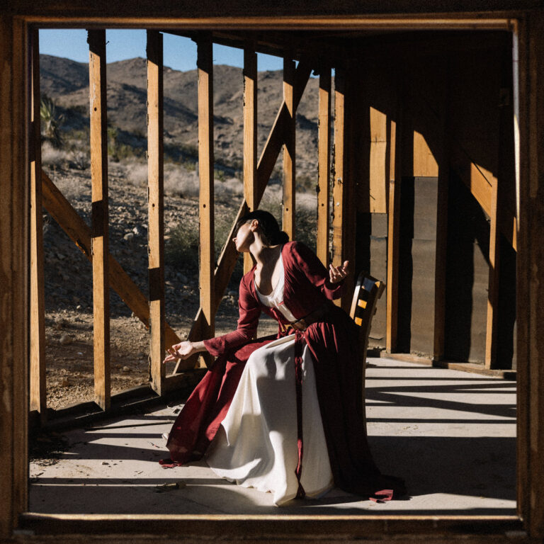Vera Sola in einem offenen Rohbau in der Wüste, im historischen Gewand – Coverbild zu „Peacemaker“, einem epischen, cineastischen Album voller Kontraste.