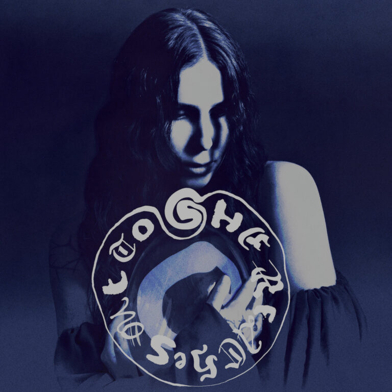 Cover von Chelsea Wolfe – She Reaches Out To She Reaches Out To She: geheimnisvolles Porträt in Blautönen mit verschlungenem Schriftkreis und düsterem Lichtspiel.