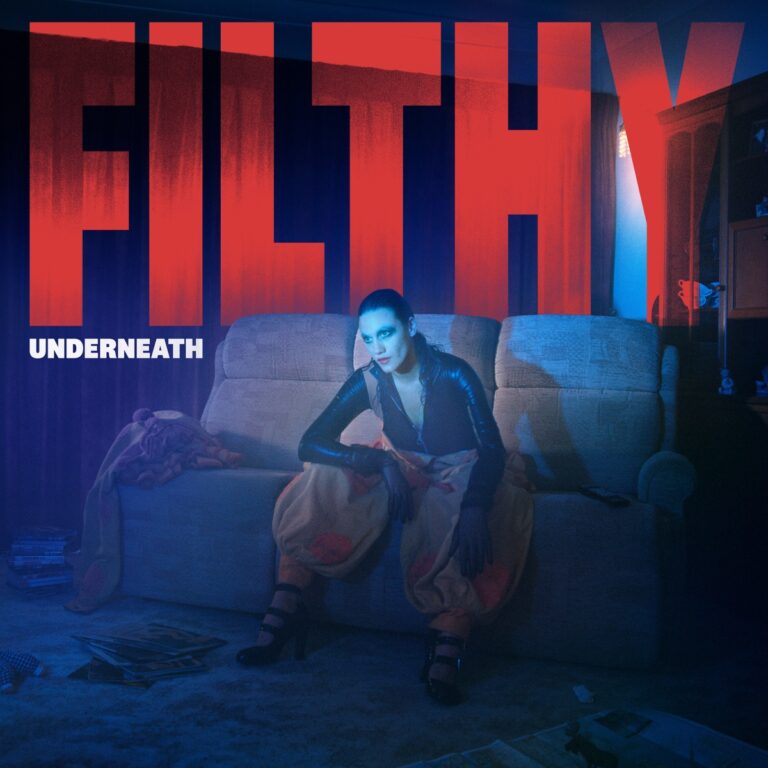 Albumcover von Nadine Shah – Filthy Underneath: Die Künstlerin sitzt in dramatischer Pose auf einem Sofa, vor leuchtend rotem Filthy-Schriftzug und blauer Lichtstimmung.