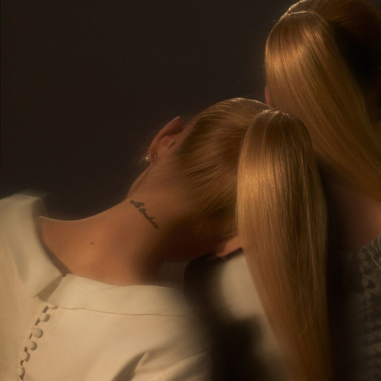 Ariana Grande mit strengem Zopf, Rückenansicht im Doppel – das verschwommene Cover von eternal sunshine spielt mit Spiegelung und Identität.