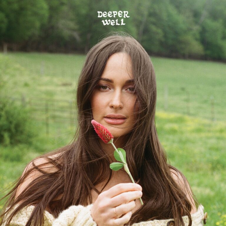 Cover von „Deeper Well“: Kacey Musgraves hält eine Blume inmitten grüner Natur, mit ruhigem Blick und sanftem Wind im Haar.