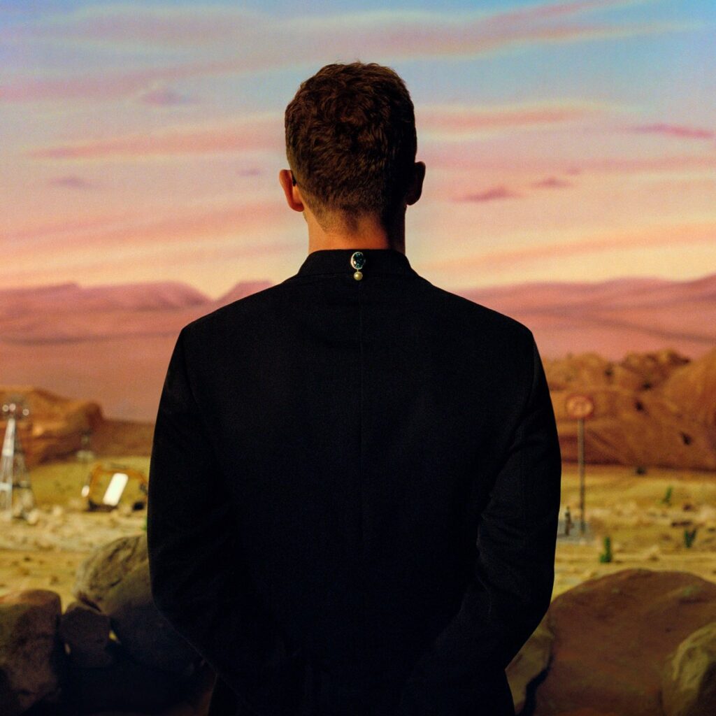 Albumcover von Justin Timberlakes „Everything I Thought It Was“ mit Rückenansicht vor surrealem Wüstenpanorama bei Sonnenuntergang.