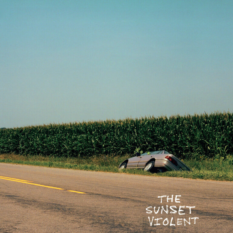 Albumcover von Mount Kimbie – The Sunset Violent zeigt ein halb im Maisfeld versunkenes Auto an einer verlassenen Landstraße unter klarem Himmel.