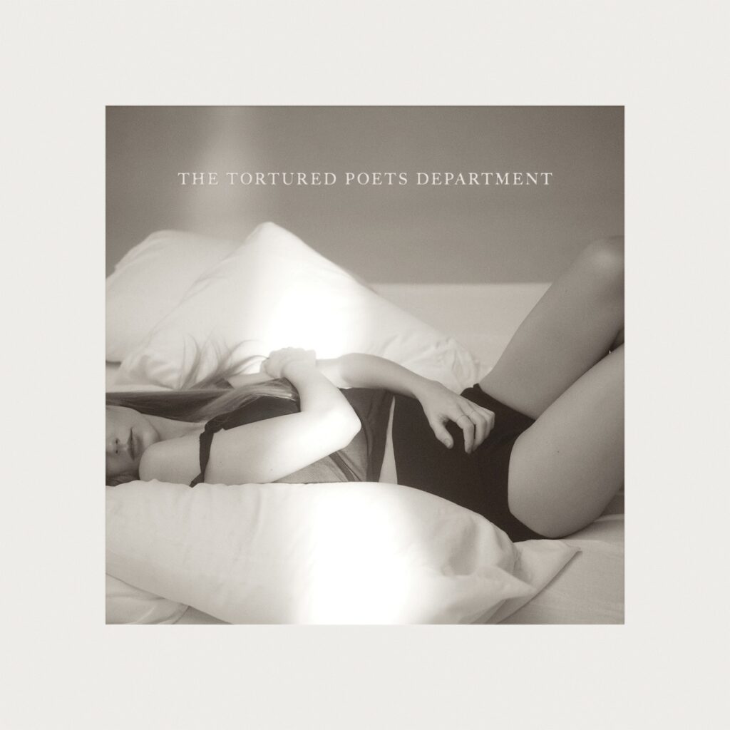 Taylor Swift liegt in Schwarz-Weiß auf einem Bett, halb verborgen, halb verletzt – das minimalistische Cover zu „The Tortured Poets Department“.