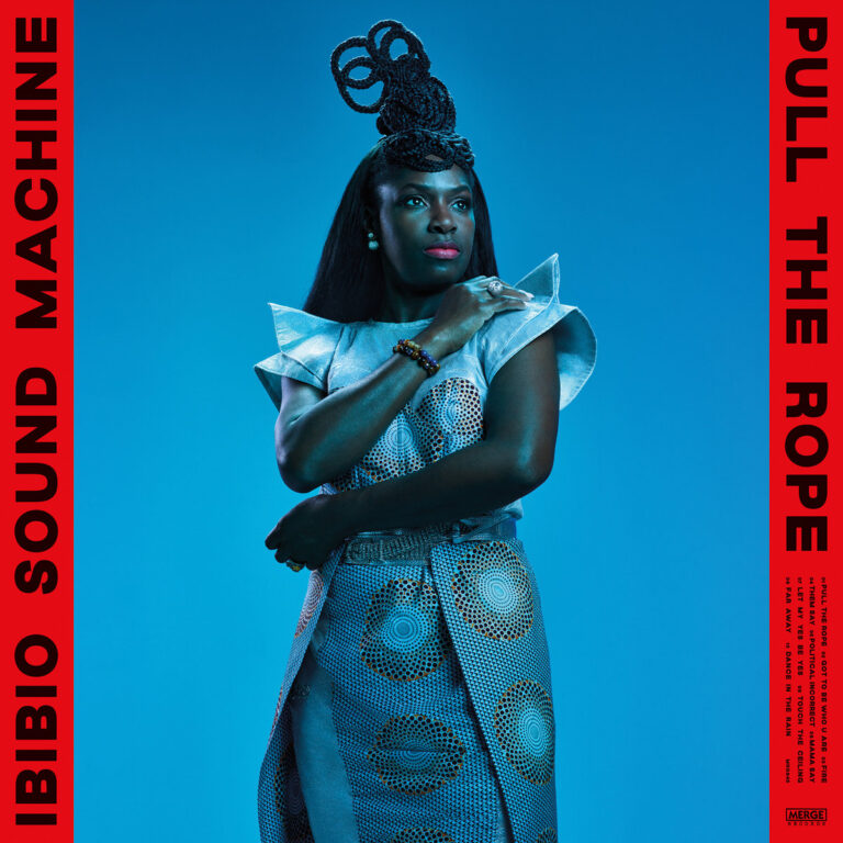 Porträt der Sängerin Eno Williams in futuristischem, silbernem Outfit vor monochrom blauem Hintergrund – Cover des Albums „Pull the Rope“ von Ibibio Sound Machine.