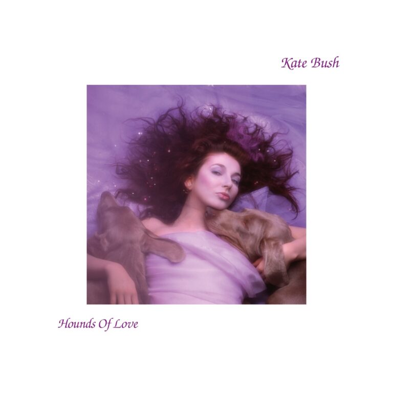 Kate Bush liegt in lila Tuch gehüllt mit zwei Hunden, umgeben von lila Licht und Glitzer.
