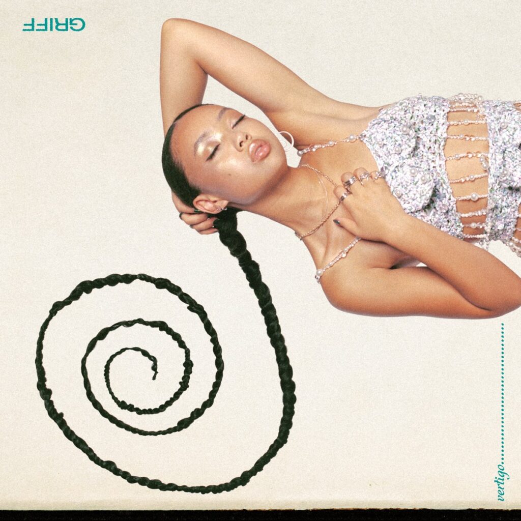 Griff liegt auf dem Cover von Vertigo mit geschlossenen Augen in einem glitzernden Outfit, ihr geflochtener Zopf spiralförmig vor ihr – ein Sinnbild für Emotionen, die sich drehen und verdichten.