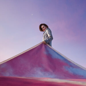 Auf dem Albumcover von My Light, My Destroyer steht Cassandra Jenkins unter einem violett-rosa Himmel und hebt ein riesiges Stofftuch in Pastellfarben – ein surrealer Akt zwischen Offenbarung und Inszenierung.