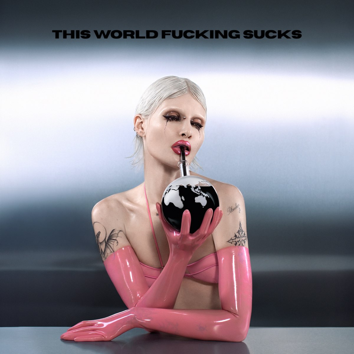 Albumcover von This World Fucking Sucks zeigt Cassyette in Latexhandschuhen und pinkem Top, wie sie durch einen Strohhalm aus einem Erdball trinkt – ein provokantes, postapokalyptisches Symbolbild mit Glam-Attitüde.