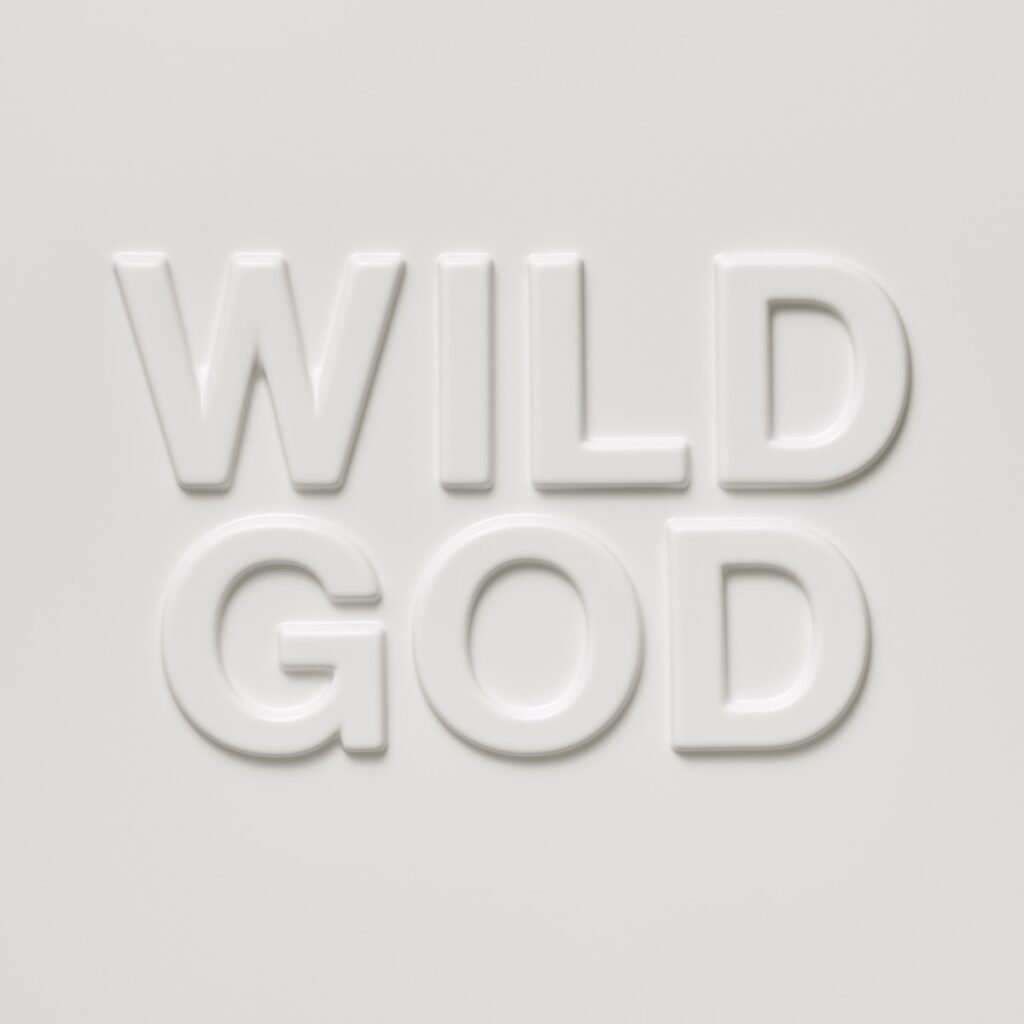 Albumcover von „Wild God“ von Nick Cave & The Bad Seeds mit geprägtem weißen Schriftzug auf hellgrauem Hintergrund.