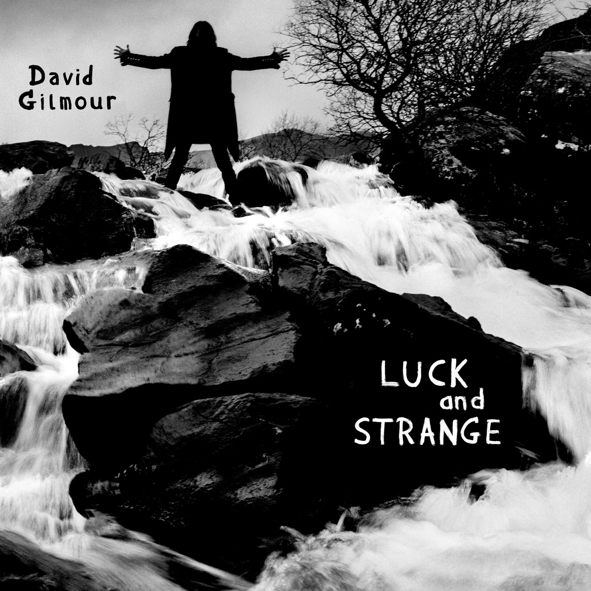 Albumcover zu „Luck and Strange“ von David Gilmour: Schwarzweiß-Foto mit Wasserfall, Felsen und Silhouette mit ausgebreiteten Armen – mystisch und erhaben.