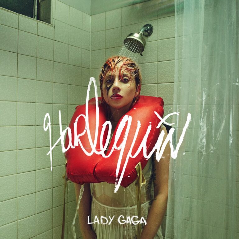 Lady Gaga steht unter einer Dusche in einem gefliesten Raum, trägt eine rote Rettungsweste und Make-up im Stil von Harley Quinn – surreal, dramatisch, ikonisch.