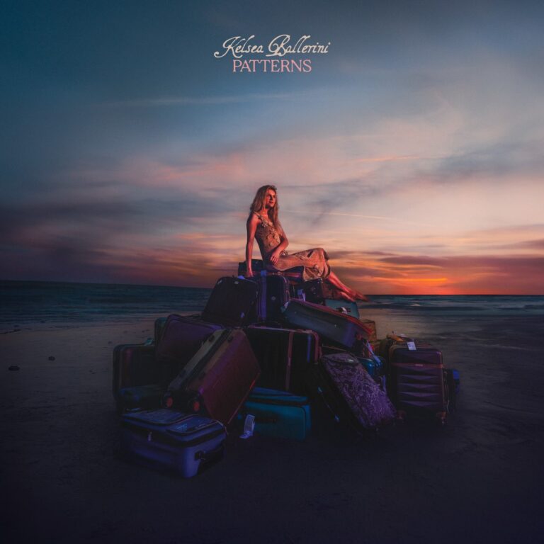 Kelsea Ballerini sitzt bei Sonnenuntergang auf einem Haufen Koffer am Strand – Cover des Albums Patterns, das emotionale Reise und Neubeginn symbolisiert.
