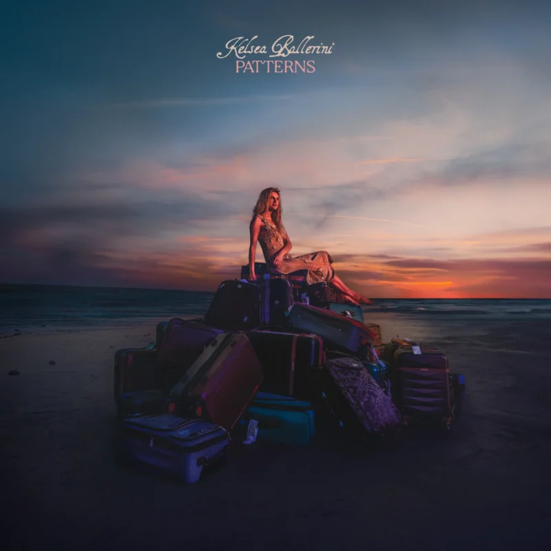 Kelsea Ballerini sitzt bei Sonnenuntergang auf einem Berg aus Koffern am Strand – Artwork zum Album „Patterns“, das persönliche Geschichten in Szene setzt.