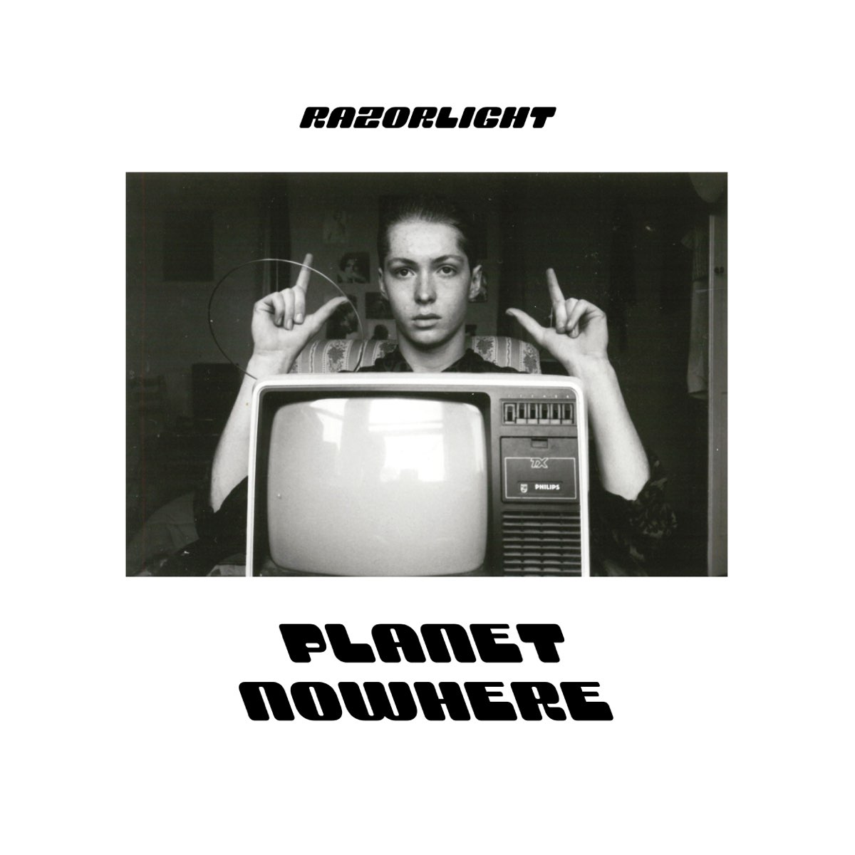Schwarz-weißes Foto eines Jugendlichen hinter einem alten Fernseher, mit Fingerzeichen wie ein Regisseur – Cover zum Razorlight-Album „Planet Nowhere“.