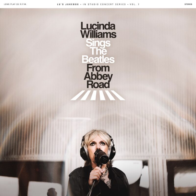 Lucinda Williams im Aufnahmestudio mit Kopfhörern und Mikrofon, über ihr das Artwork „Lucinda Williams Sings The Beatles From Abbey Road“.