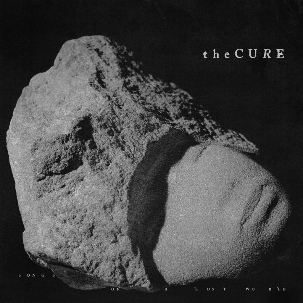 Albumcover von Songs of a Lost World von The Cure: ein halb verwitterter Sandstein mit angedeutetem Gesicht im Dunkelgrau, symbolisch für Vergänglichkeit.