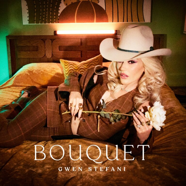 Gwen Stefani liegt im Anzug und Cowboyhut auf einem Bett, mit weißer Rose in der Hand – Cover des Country-Pop-Albums „Bouquet“.