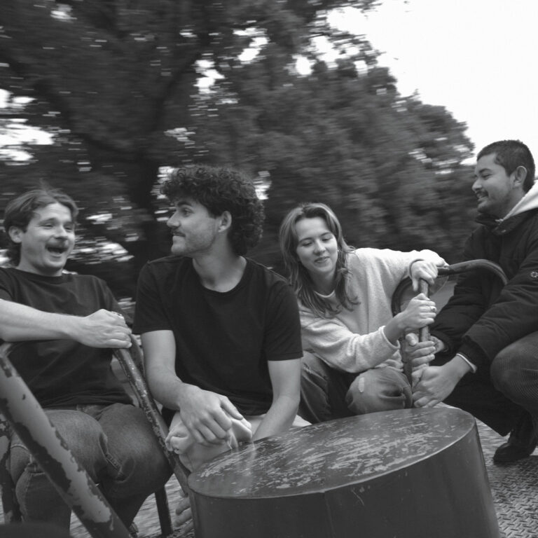 Schwarz-weißes Foto von vier Bandmitgliedern auf einem sich drehenden Spielplatz-Karussell – stimmungsvolles Cover zum Debütalbum „Lush Life“ von The Belair Lip Bombs.