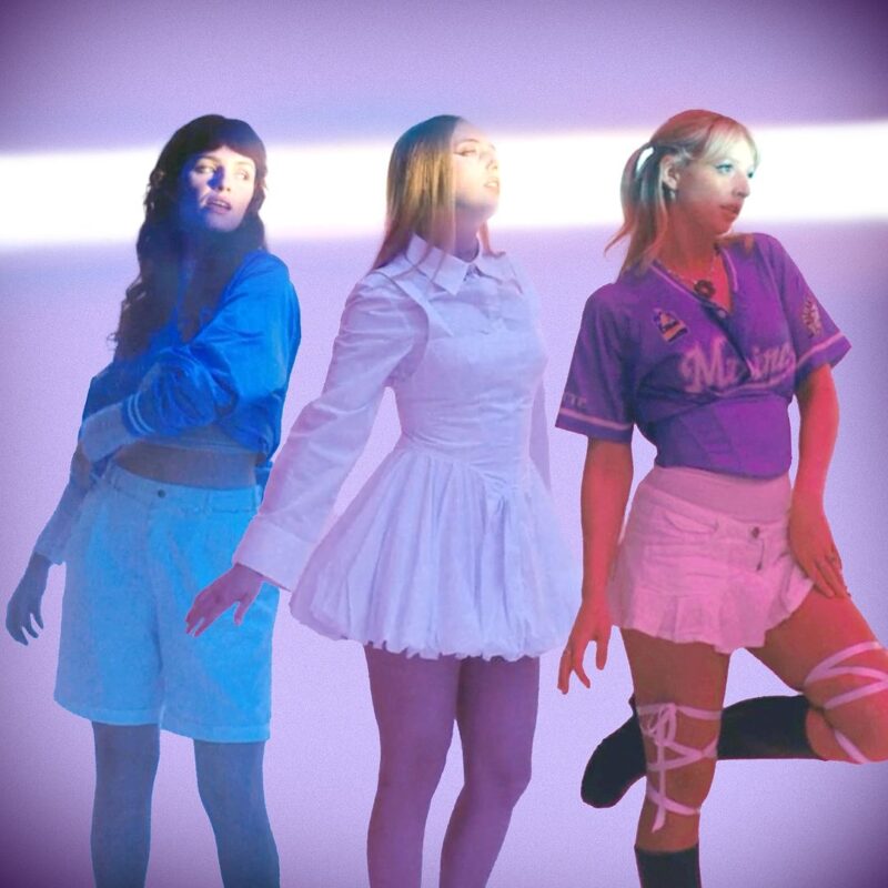 Die drei Mitglieder der Band Blusher in farbigem Licht vor lila Hintergrund – Szene aus dem Artwork zur Single Somebody New.