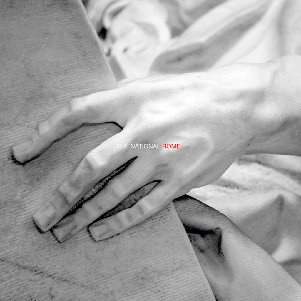 Detailaufnahme einer klassisch anmutenden Skulpturenhand, die eine raue Fläche umfasst – Artwork des Livealbums Rome von The National.