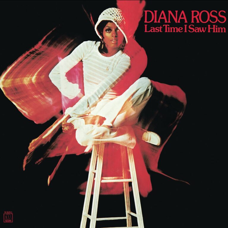 Diana Ross sitzt auf einem Hocker, trägt einen weißen Pullover und einen Hut, Hintergrund in kräftigen Farben.