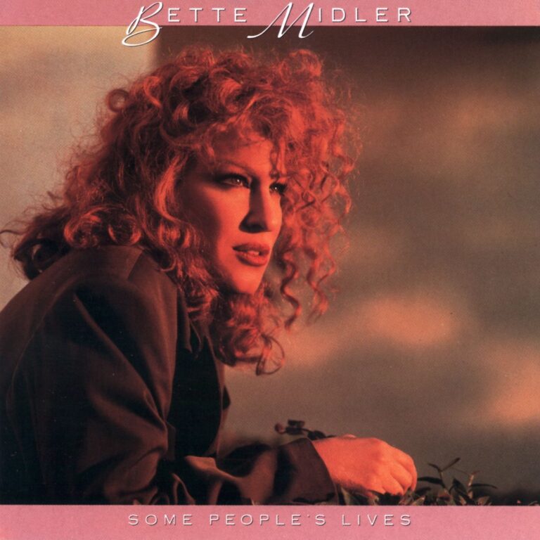 Bette Midler mit lockigem Haar, blickt nachdenklich in die Ferne vor einem dramatischen Himmel.